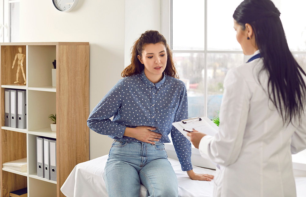 Young woman experiencing abdominal pain in doctor's office.