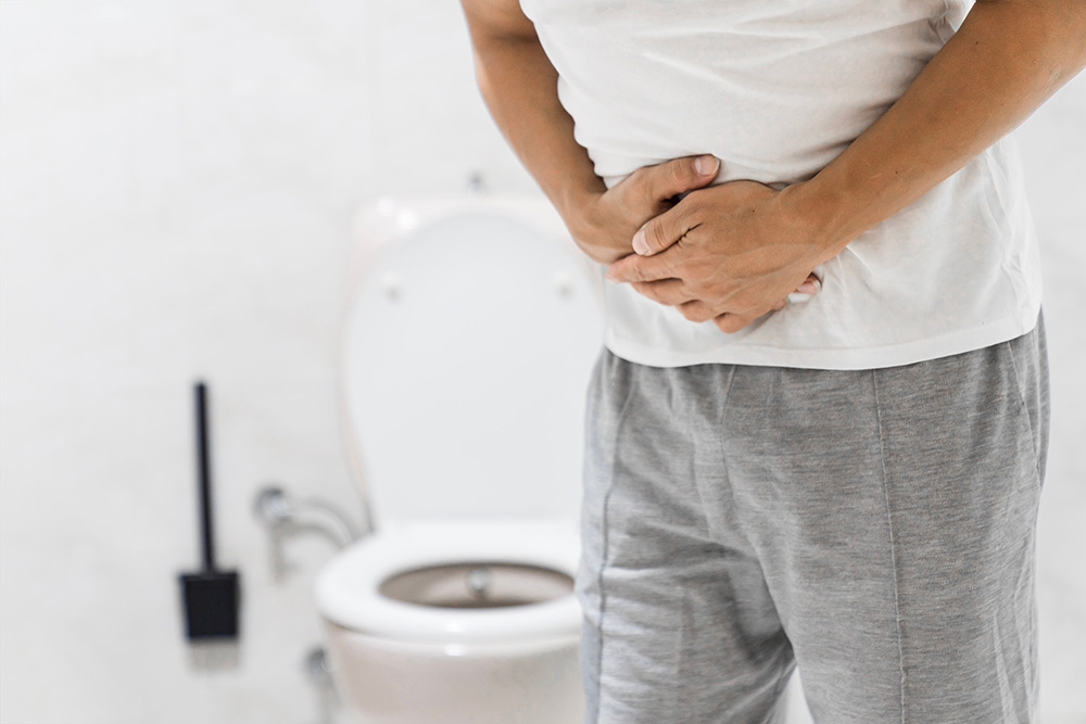 Man with diarrhea holds his stomach in the bathroom.
